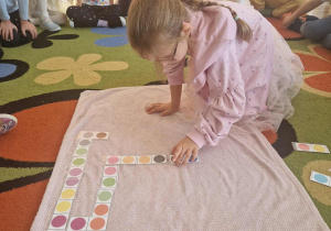 Dziewczynka uklada domino z kolorowych kropek
