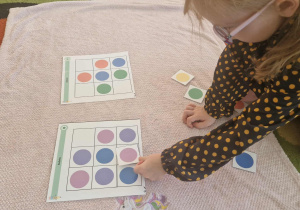 Dziewczynka uklada domino z kolorowych kropek