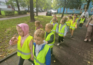 Dzieci w kamizelkach odblaskowych idą na pobliskie skrzyżowanie