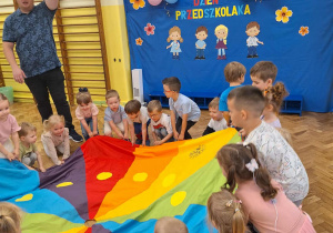Dzieci unoszą kolorową chustę animacyjną