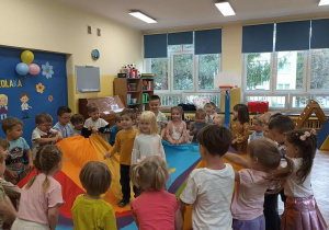 Dwoje dzieci stoi w środku kolorowej chusty