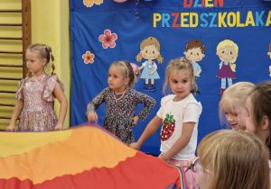 Dzieci trzymają kolorową chustę
