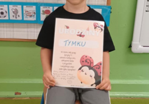 Chłopiec pokazuje swój urodzinowy dyplom.