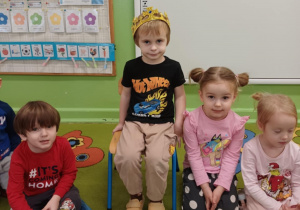 Chłopiec siedzi w koronie wśród dzieci