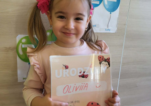 Dziewczynka stoi z dyplomem