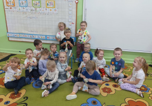 Dzieci pokazują prezenciki, które dostały od chłopca jako poczęstunek z okazji jego urodzin.