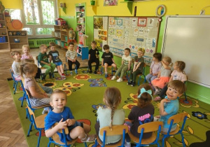 Chłopiec siedzi wśród dzieci w koronie