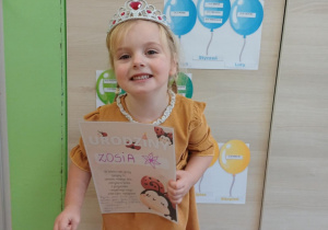 Dziewczynka stoi z dyplomem urodzinowym