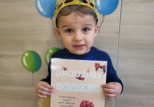Chłopiec stoi z dyplomem urodzinowym