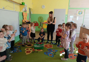 Chłopiec siedzi z koroną dzieci i Pani stoją i klaszczą