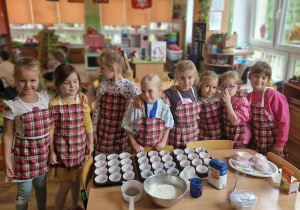 Dziewczynki w fartuszkach w kratę przygotowują się do przygotowania muffinek