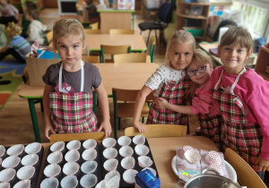 Dziewczynki w fartuszkach w kratę przygotowują się do przygotowania muffinek