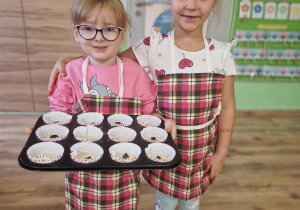 Dwie dziewczynki prezentują blachę z muffinkami