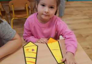 Dziewczynka koloruje krawat dla kolegi z grupy.