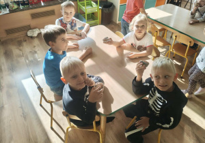 Dzieci siedzą przy stoliku i jedzą muffiny