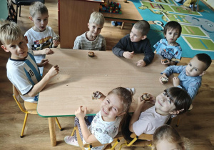 Dzieci siedzą przy stoliku i jedzą muffiny