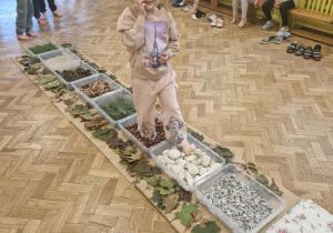 Dziewczynka przechodzi na boso po ścieżce sensorycznej