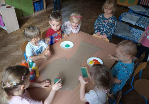 Dzieci przygotowują się do malowania farbami drzewa