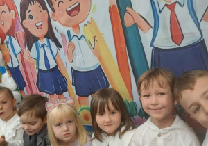 Dzieci pozują do zdjęcia na tle kolorowej dekoracji