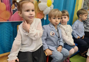Dzieci pozują do zdjęcia na tle kolorowej dekoracji