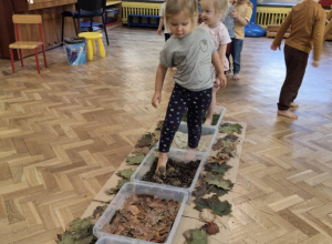 Dziewczynka przechodzi na boso po ścieżce sensorycznej.