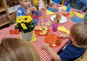 Dzieci siedzą przy stole i degustują owocowe ciasto