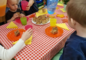 Dzieci siedzą przy stole i piją sok