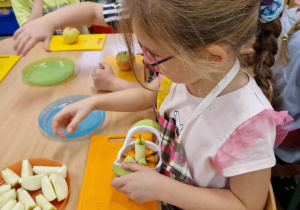 Dziewczynka dzieli jabłka na ćwiartki