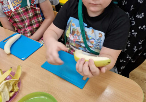 Chłopiec obiera banana ze skórki