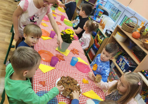 Starsze dzieci pomagają nalać sok młodszym dzieciom