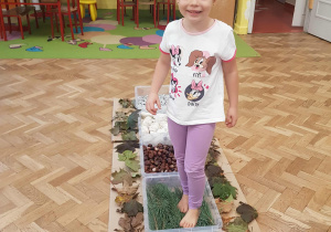 Dziewczynka chodzi boso po ścieżce sensorycznej.