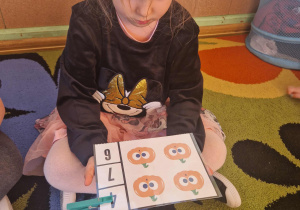 Dziewczynka przelicza dynie na obrazku