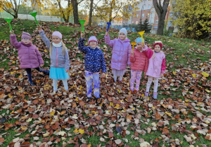 Dziewczynki unoszą w góre akcesoria do grabienia