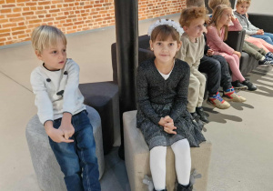 Dzieci siedzą na kanapach w oczekiwaniu na spektakl