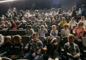 Dzieci siedzą na widowni w oczekiwaniu na spektakl