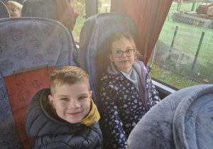 Dziewczynka i chlłopiec siedzą w autokarze