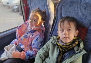 Dziewczynka i chlłopiec siedzą w autokarze