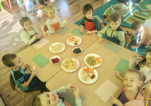 Dzieci nadziewaja owoce na patyki szaszłykowe