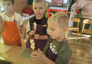 Dzieci nadziewaja owoce na patyki szaszłykowe