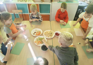 Dzieci nadziewaja owoce na patyki szaszłykowe