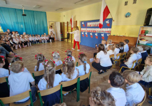 Pani w biało czerwonym stroju prowadzi uroczystość z okazji Dnia Niepodległości