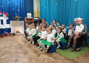 Dzieci siedzą na ławeczkach