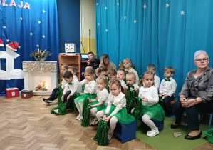 Dzieci z I grupy siedzą na ławeczkach z pomponami