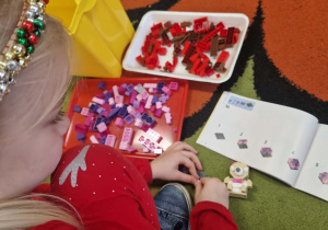 dziewczynka układa misia z klocków lego