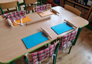 Na stole leżą kolorowe taci wałki i fartuszki