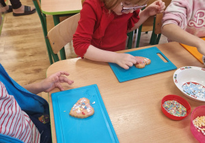 Dziewczynka ozdabia ciasteczko posypkami