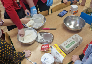 Dzieci przesypują mąkę przez sitko