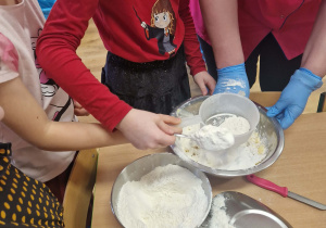 Dzieci przesypują mąkę przez sitko