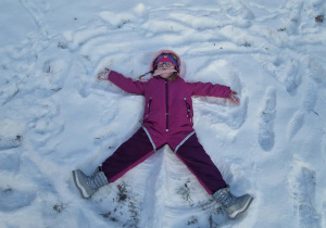 Dziewczynka robi na śniegu aniołka