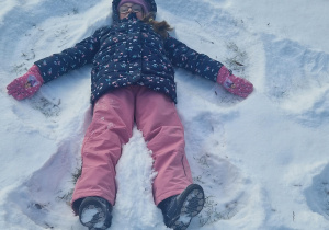 Dziewczynka robi na śniegu aniołka